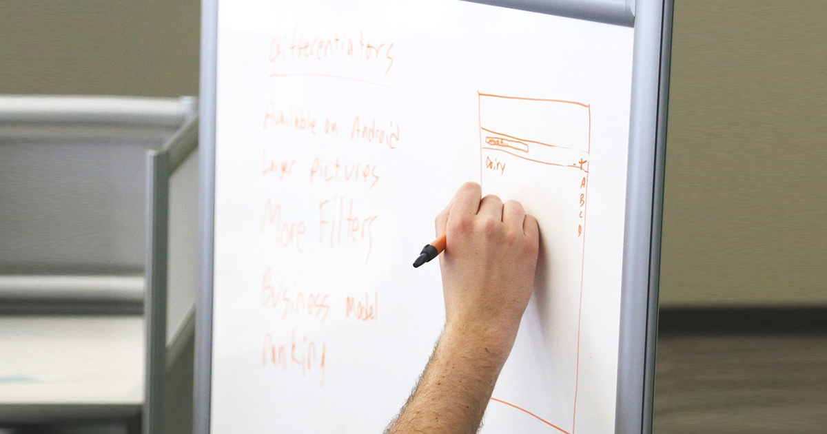 Mano che scrive su una lavagna bianca alcuni appunti